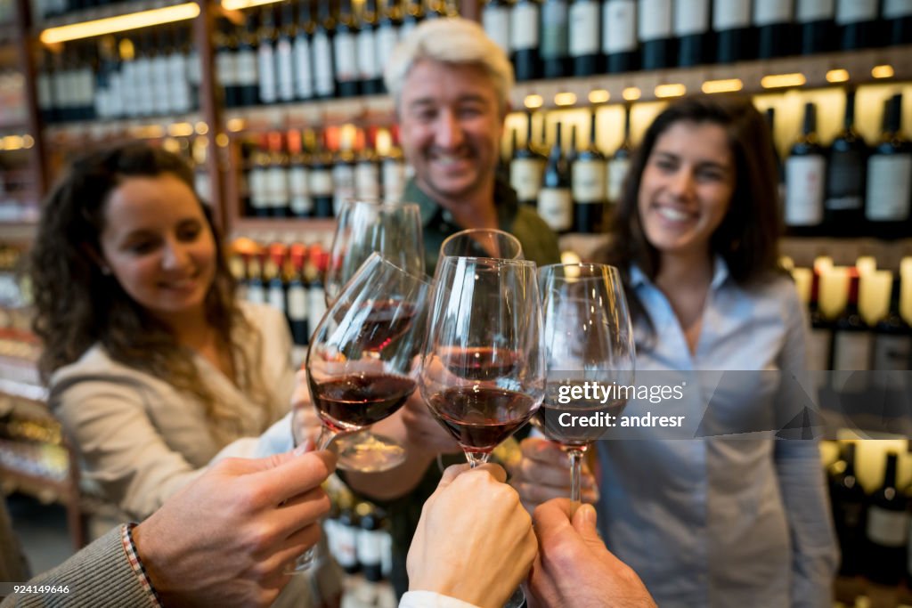 Happy group of friends at a winery tasting red wine and toasting