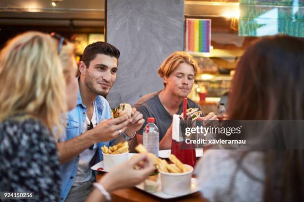 amigos masculinos y femeninos con comida en restaurante - male burger eating fotografías e imágenes de stock