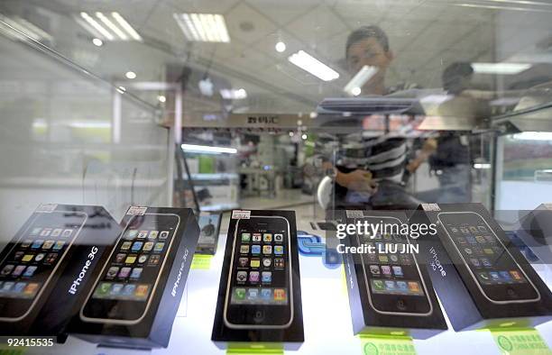 China-telecom-mobile-technology-Apple-iPhone,FOCUS A salesman sits behind a display showing real Apple iPhones in a counter in Beijing on October 28,...