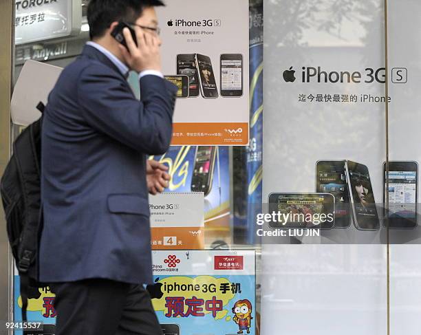 China-telecom-mobile-technology-Apple-iPhone,FOCUS A man talks on his phone as he walks past posters promoting the Apple iPhones at a store in...