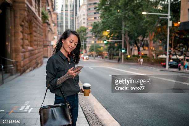 jovem empresária esperando por táxi em sydney - sudeste asiático etnia oriental - fotografias e filmes do acervo