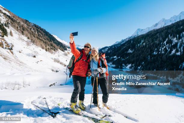 couple backcountry ski above swiss village after fresh snow - pantalon rouge photos et images de collection
