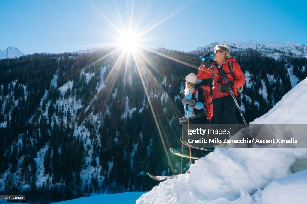 Couple backcountry ski above Swiss valley after fresh snow