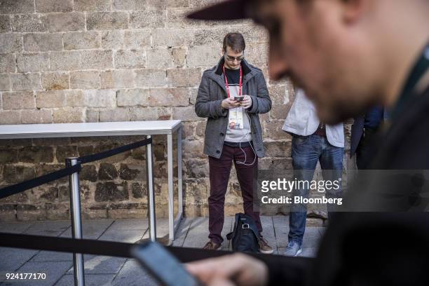 Attendees browse smartphones outside a launch event ahead of the Mobile World Congress in Barcelona, Spain, on Sunday, Feb. 25, 2018. At the wireless...