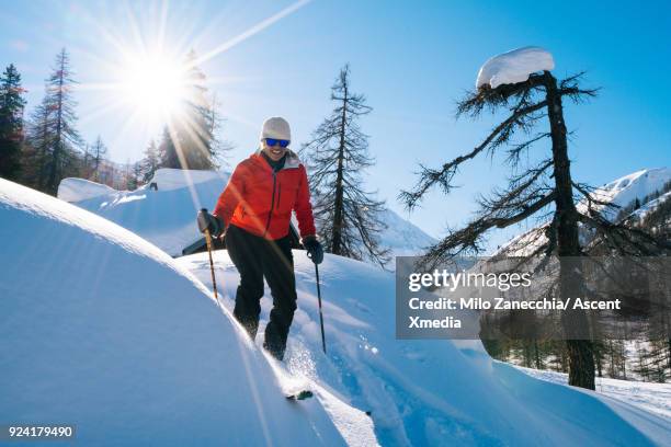 woman backcountry skis in swiss valley after fresh snow - ski pants stock-fotos und bilder