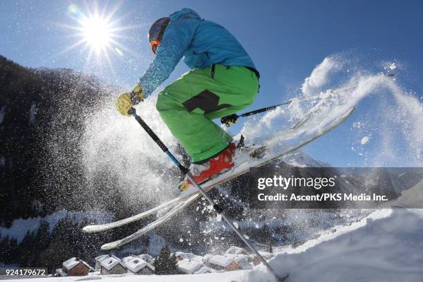 young man in mid air jump above swiss village after fresh snow - ski pants stockfoto's en -beelden