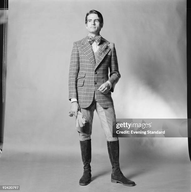 Male fashion model wearing a checked jacket and bow tie with suede boots, September 1972.