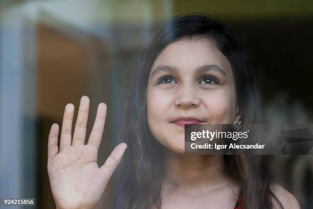 junges mädchen hinter fensterglas - child saluting stock-fotos und bilder