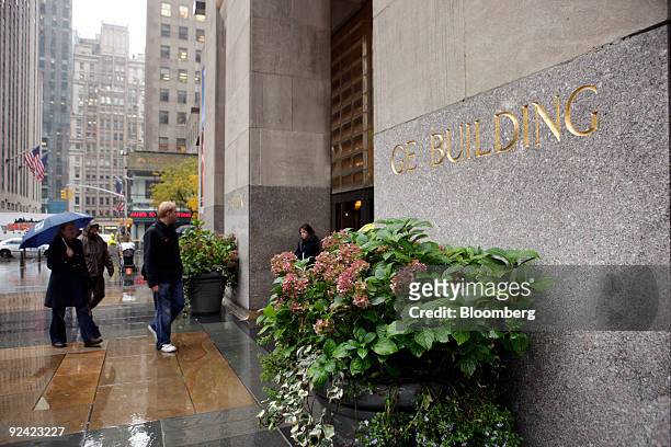 Pedestrians walk near the GE building, home of NBC television network studios at 30 Rockefeller Plaza in New York, U.S., on Wednesday, Oct. 28, 2009....