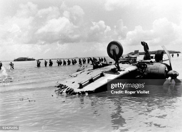 World War II. Pacific front. Guam . Marines going towards Agat Beach, July 1944. In the foreground, the wreck of a Japanese airplane.