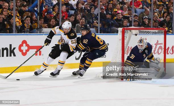 Sean Kuraly of the Boston Bruins controls the puck against Nathan Beaulieu and Chad Johnson of the Buffalo Sabres during an NHL game on February 25,...