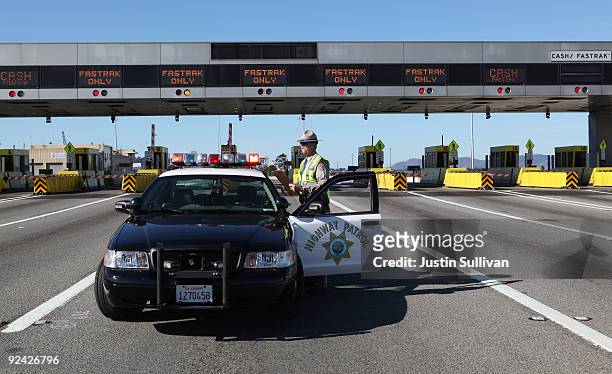 California Highway Patrol officer Rick Baller stands next to his car as he guards the closed toll plaza leading to the San Francisco Bay Bridge...