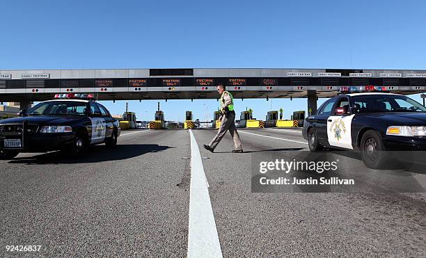 California Highway Patrol officer Rick Baller walks to his car as he guards the closed toll plaza leading to the San Francisco Bay Bridge October 28,...