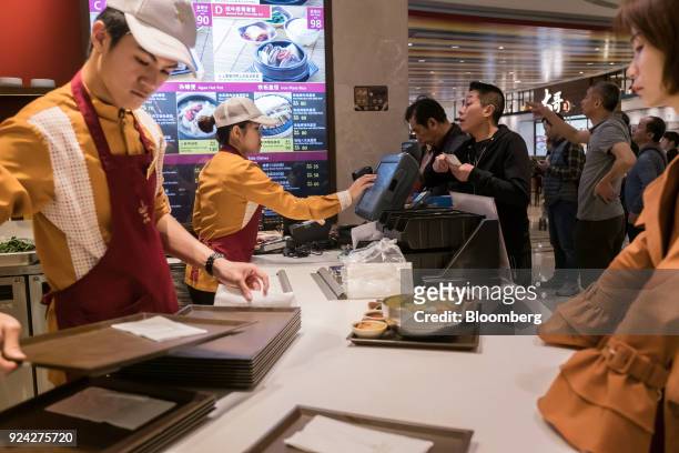 Employees take customers' orders at a fast food restaurant in the Promenade Shops shopping area of the Galaxy Macau casino and hotel, developed by...