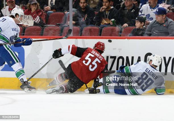 Ben Hutton of the Vancouver Canucks plays the puck over Jason Demers of the Arizona Coyotes and Sam Gagner of the Canucks during the first period at...