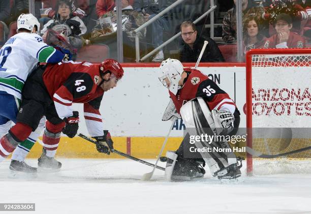 Goalie Darcy Kuemper of the Arizona Coyotes stops the puck as Jordan Martinook of the Coyotes and Daniel Sedin of the Vancouver Canucks battle on the...