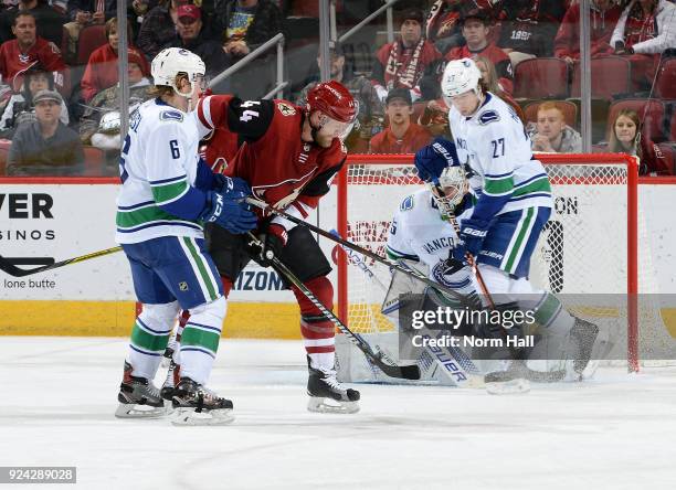 Alex Goligoski of the Arizona Coyotes tries to re-direct the puck between Brock Boeser, Ben Hutton and goalie Jacob Markstrom of the Vancouver...