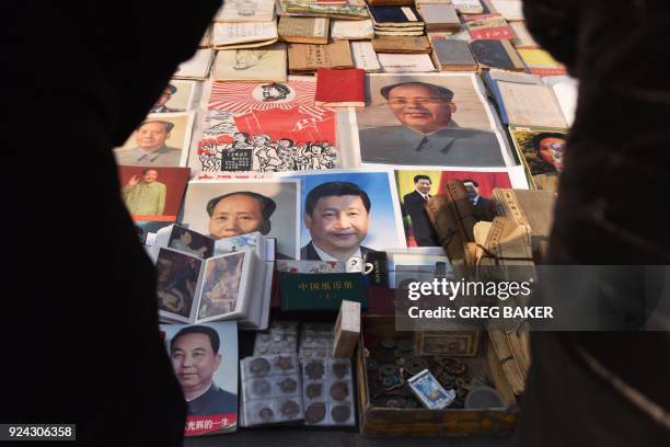 Customers look at posters of Chinese President Xi Jinping , and late communist leader Mao Zedong , at a market in Beijing on February 26, 2018. Xi...