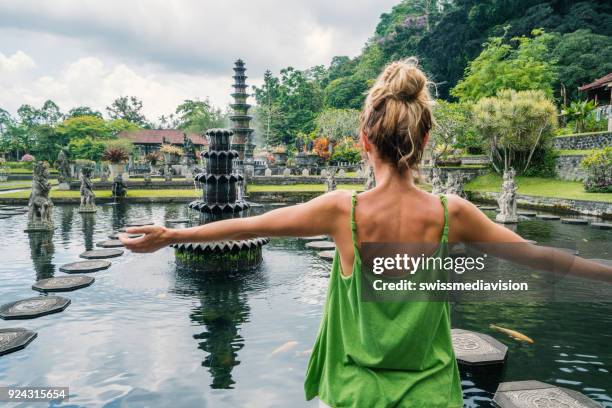 jovem mulher abraçando tirta gangga templo, bali, indonésia - bali - fotografias e filmes do acervo