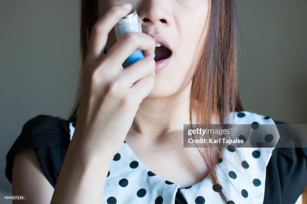 A woman is using an asthma inhaler