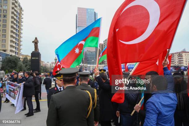 People holding banners and flags arrive to place carnations at "Ana feryadi" monument, during the 26th anniversary of 'Khojaly Massacre', which...