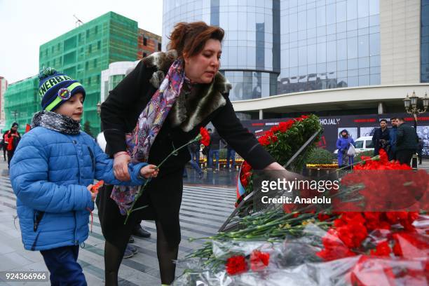 People holding banners and flags arrive to place carnations at "Ana feryadi" monument, during the 26th anniversary of 'Khojaly Massacre', which...