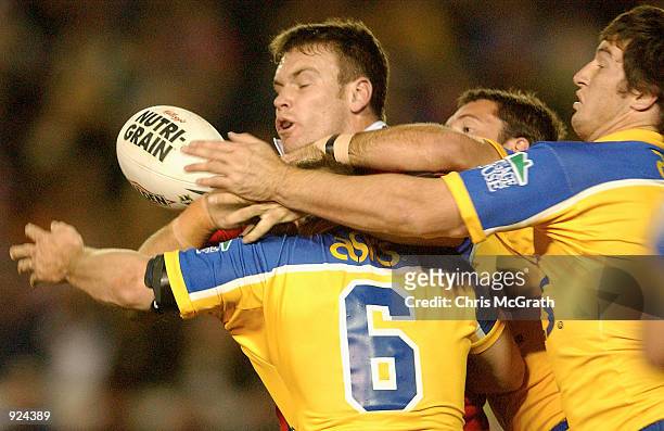 Josh Perry of the Knights is tackled by Adam Dykes and Nathan Hindmarsh of the Eels during the Round 17 NRL match between the Newcastle Knights and...