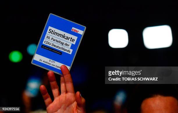 Delegate of the conservative Christian Democratic Union party holds up his voting card during the CDU party congress on February 26, 2018 in Berlin....