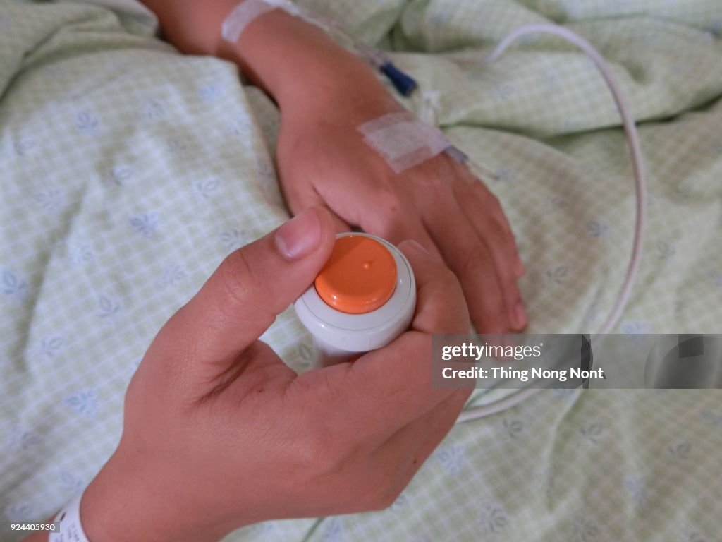 Hand With Iv Drip On Bed In Hospital and a Buzzer To Call Nurse