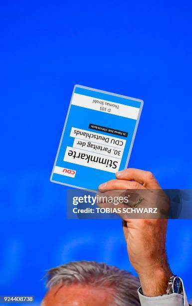 Christian Democratic Union politician Thomas Strobl holds up his voting card during a vote at the party's congress on February 26, 2018 in Berlin....