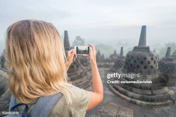 travel girl takes mobile phone picture of borobudur temple, indonesia - wonderlust computer stock pictures, royalty-free photos & images