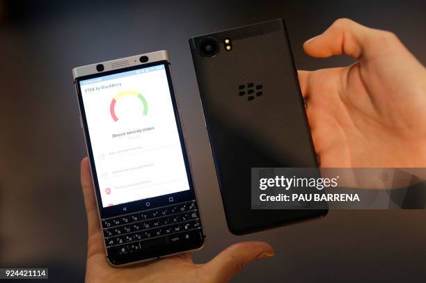 Hosts hold Blackberry KEYone mobilephones at the Mobile World Congress , the world's biggest mobile fair, on February 26, 2018 in Barcelona. The...