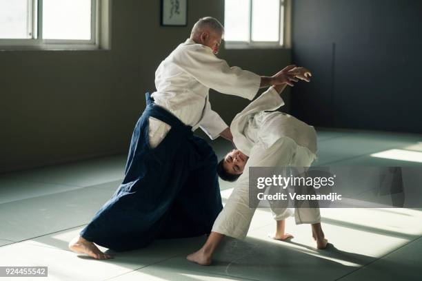 teen boy with his sansei practicing in dojo - aikido stock pictures, royalty-free photos & images
