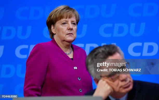 German Chancellor and leader of the conservative Christian Democratic Union party Angela Merkel walks past outgoing German Interior Minister Thomas...