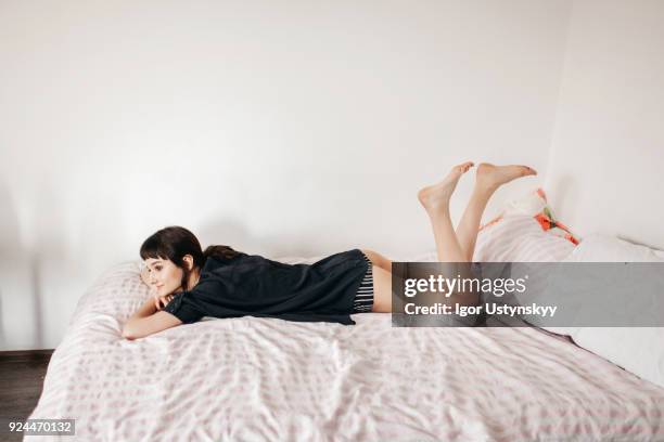 portrait of woman lying on bed and smiling - piernas en el aire fotografías e imágenes de stock