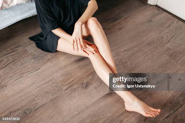 young woman massaging her leg in room - hand on knee stock pictures, royalty-free photos & images