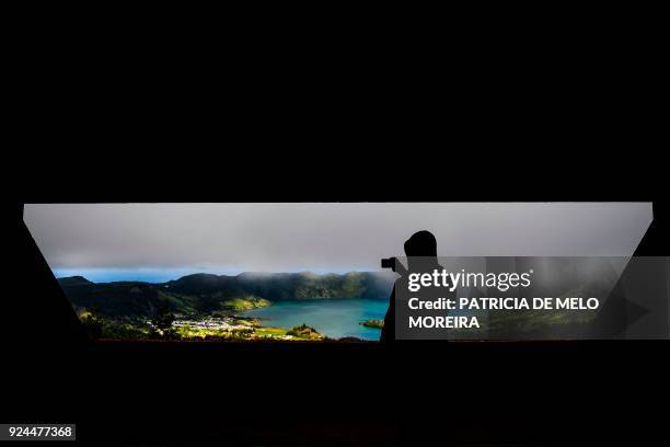 Tourist takes pictures of Sete Cidades lagoon from inside an abandoned hotel that has become one of the most visited viewpoints by tourists in Sao...