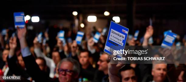 Delegates of the conservative Christian Democratic Union party hold up their voting cards during the CDU party congress on February 26, 2018 in...