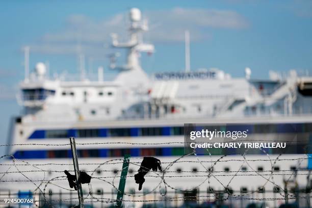 This Picture taken on February 26 shows gloves on Ouistreham harbor's barbed wire fence, near Caen, Northwestern France. More than a year after the...