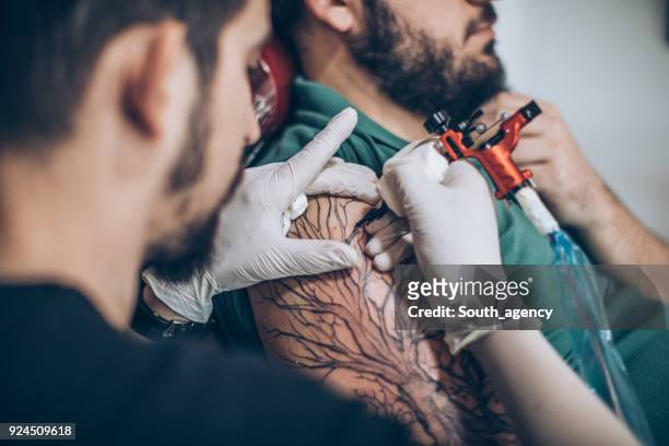 artist working on tattoo - tattoo spectacular stock pictures, royalty-free photos & images