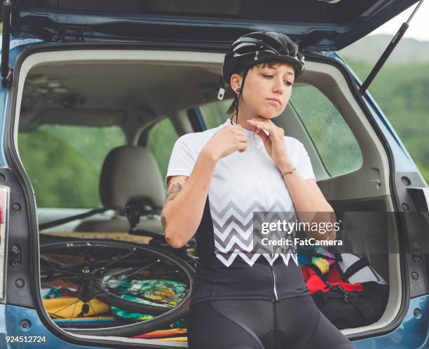 female cyclist puts on her biking gear and zips up her jersey - road cycling stock pictures, royalty-free photos & images