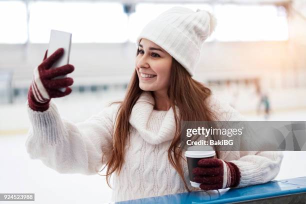 giovane donna pattinaggio su ghiaccio e uso di uno smartphone - woman looking through ice foto e immagini stock