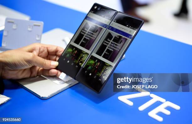 Person holds the new ZTE's dual screens foldable smartphone AXON on the first day of the Mobile World Congress on February 26, 2018 in Barcelona. The...