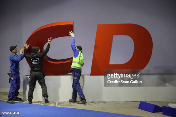 Workers dismantle the CDU logo of the German Christian Democrats following the conclusion of the 30th party congress on February 26, 2018 in Berlin,...
