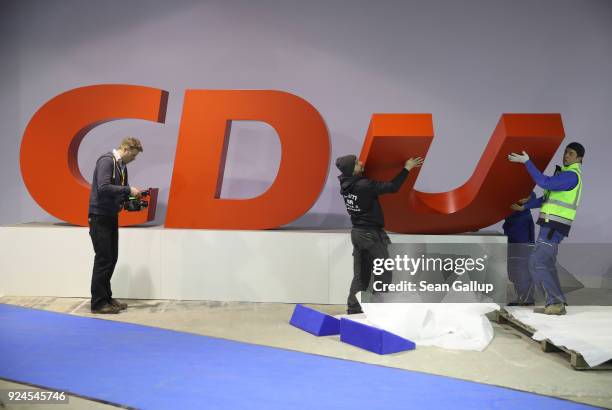 Workers dismantle the CDU logo of the German Christian Democrats following the conclusion of the 30th party congress on February 26, 2018 in Berlin,...