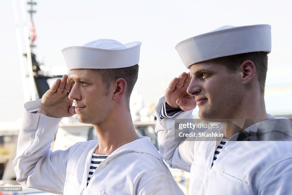 Two Navy sailors saluting on a ship