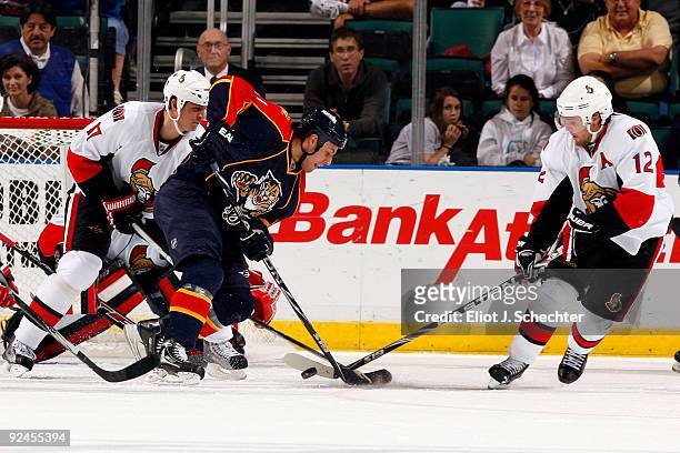 Gregory Campbell of the Florida Panthers battles for the puck against Mike Fisher and Filip Kuba of the Ottawa Senators at the Bank Atlantic Center...
