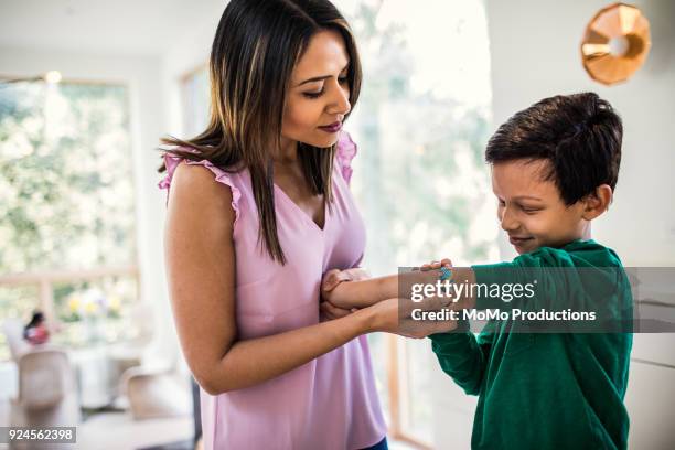 mother putting band-aid on son - wundverband stock-fotos und bilder