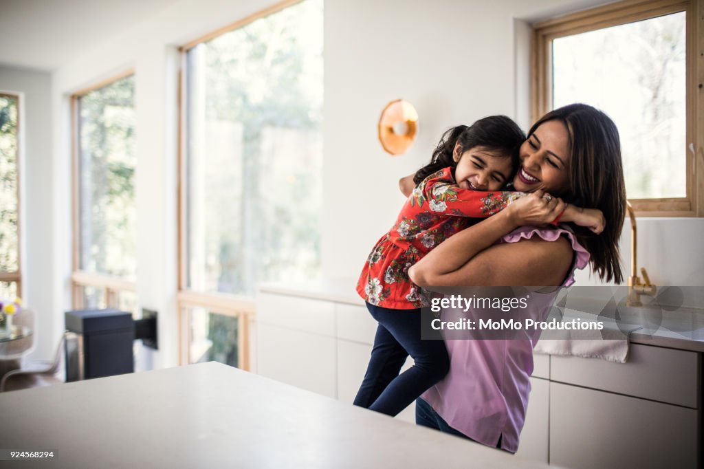 Mother and daughter embracing in kitchen