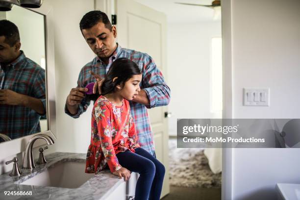 father brushing daughters hair in bathroom - alleinerzieher stock-fotos und bilder